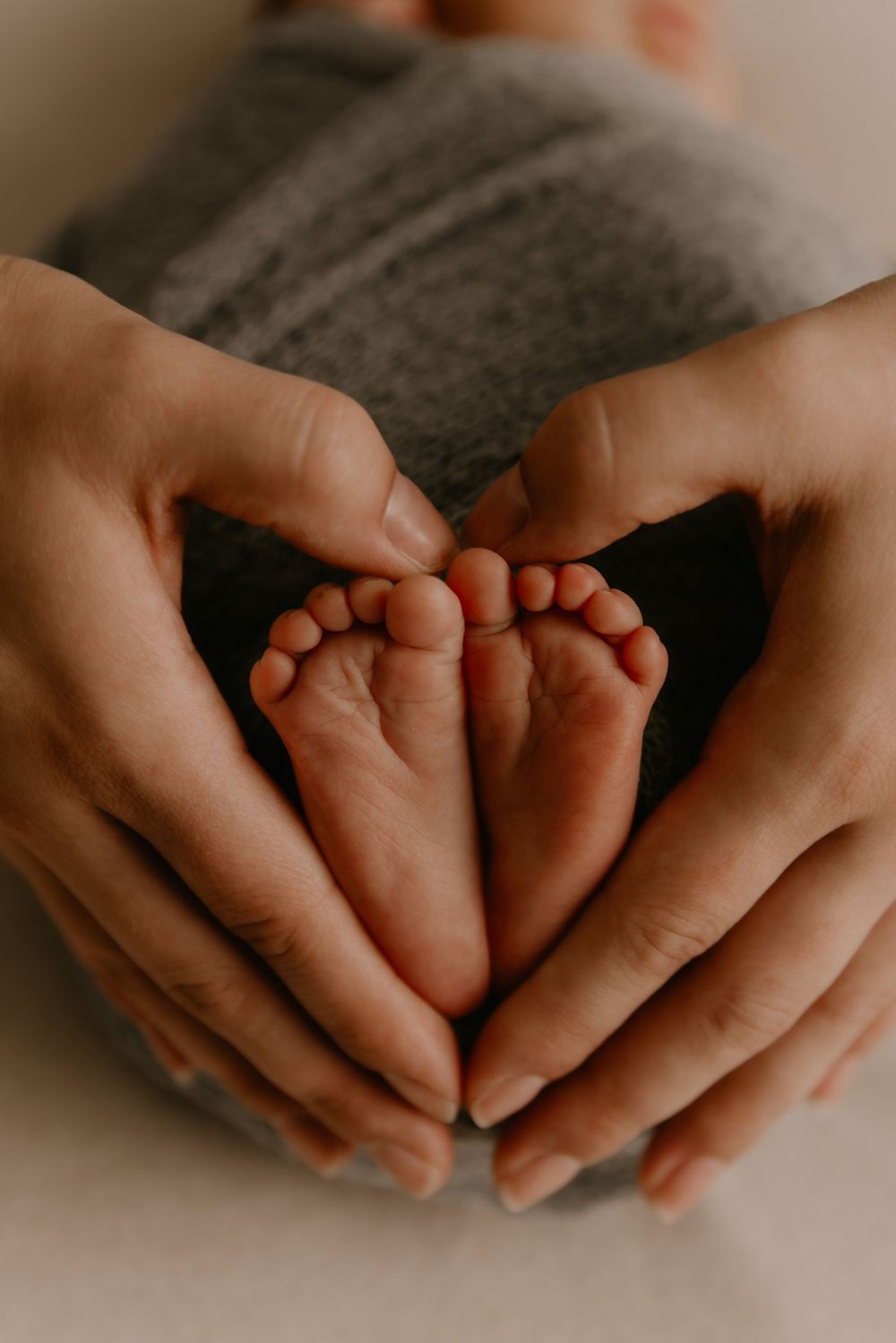 Adult hands gently cradle tiny baby feet in a heartwarming series of intimate black and white photographs.