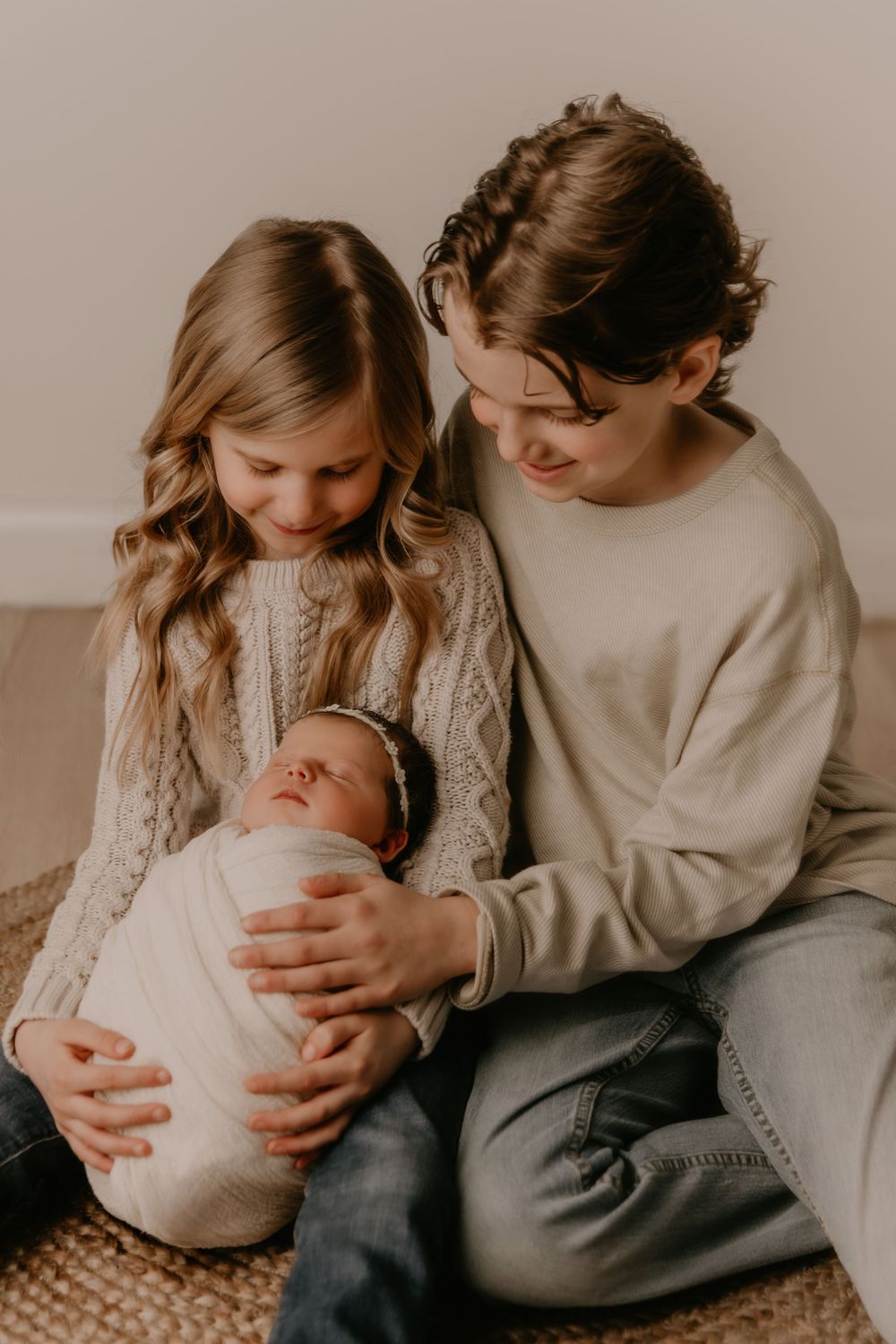 Intimate family moment captured in warm tones showing parents bonding with their newborn baby in a cozy setting.