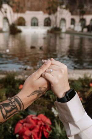 Newly engaged, holding hands with ring showing in front of duck pond at Balboa Park, San Diego CA