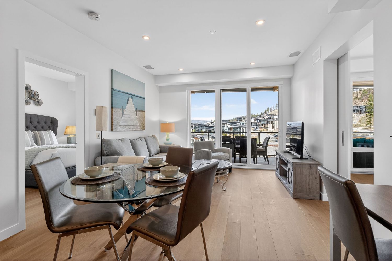 Modern luxury apartment interior with open floor plan featuring white walls, hardwood floors, and contemporary furnishings.