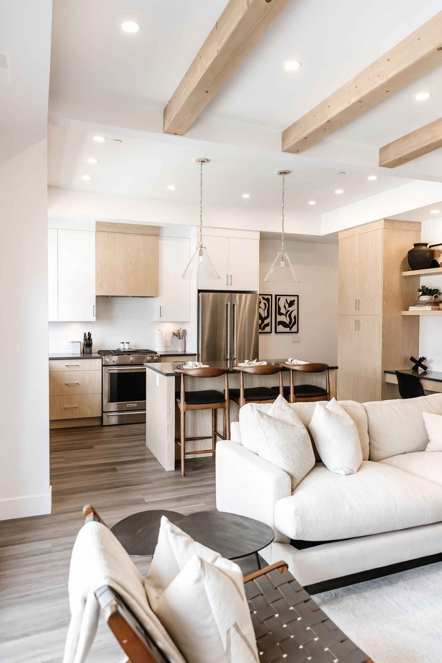 Modern open concept living room and kitchen with white sofa and wooden beam ceiling details.