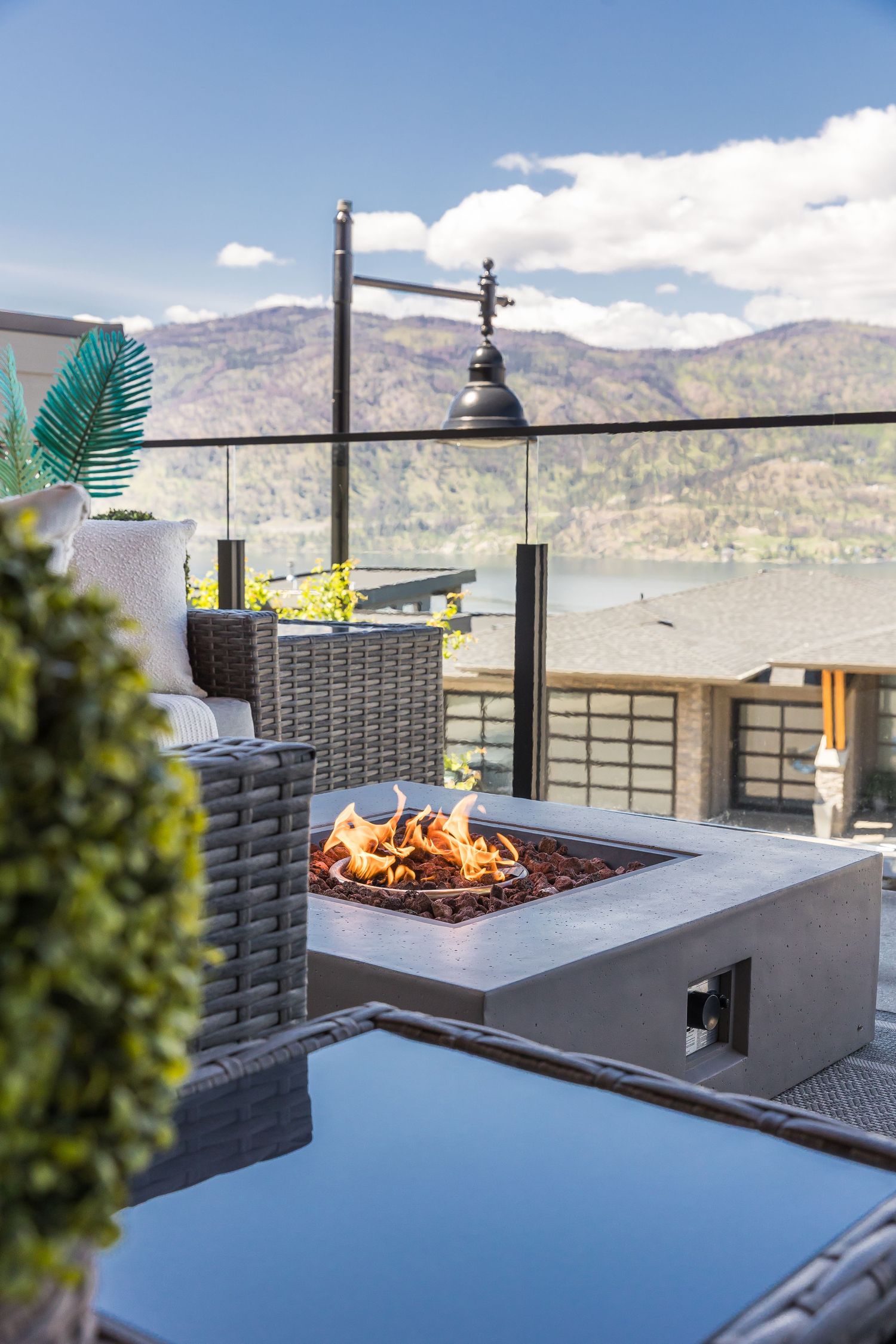 Sleek modern fire pit table on outdoor patio with mountain vista and blue sky backdrop in a west Kelowna Airbnb