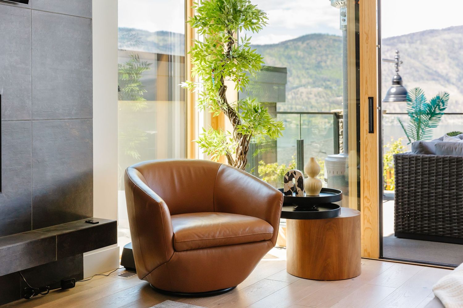 Luxurious brown leather accent chairs beside wooden side table with panoramic mountain views in a west Kelowna Airbnb