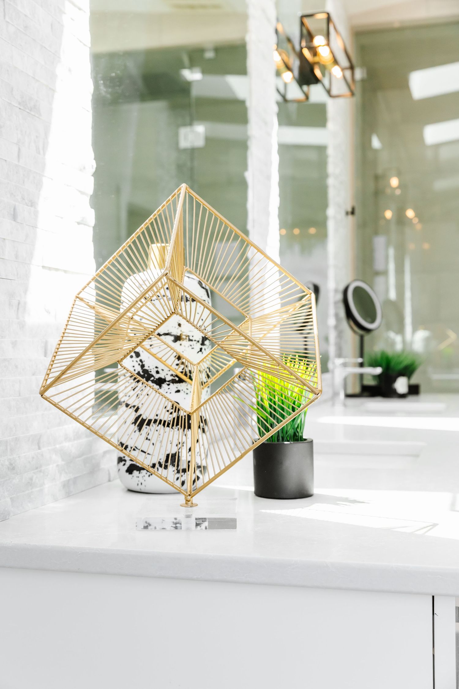 Artistic gold geometric sculptures displayed on white bathroom windowsill with natural lighting in a west Kelowna Airbnb