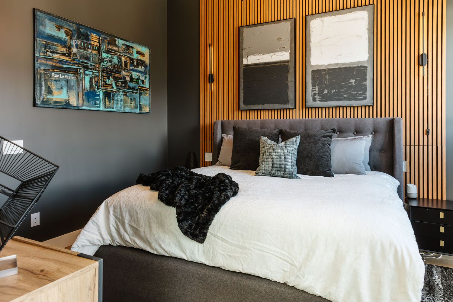 Modern bedroom interior with wooden slat accent wall and black nightstand in a Kelowna Airbnb
