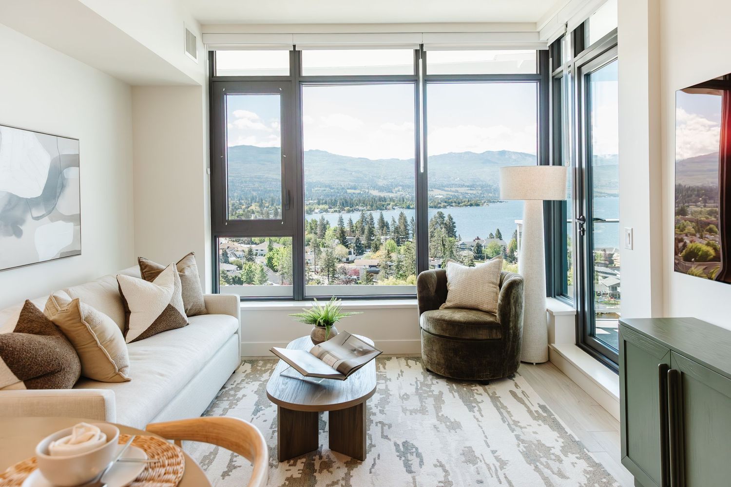 Spacious living room with panoramic windows offering mountain views and modern furnishings in a west Kelowna Airbnb