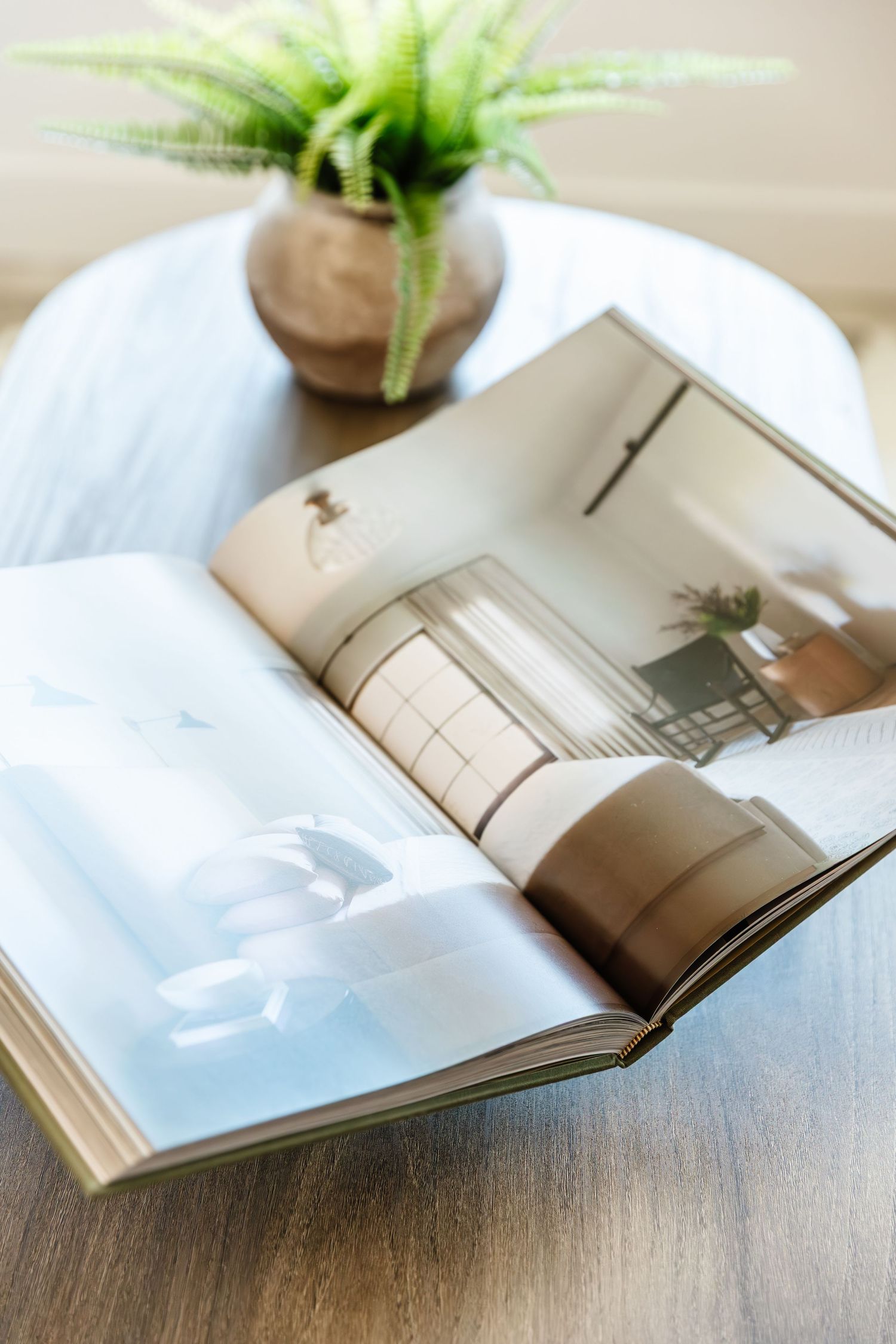 Open magazine on wooden table with green plant decoration showing minimalist interior design spreads in a west Kelowna Airbnb