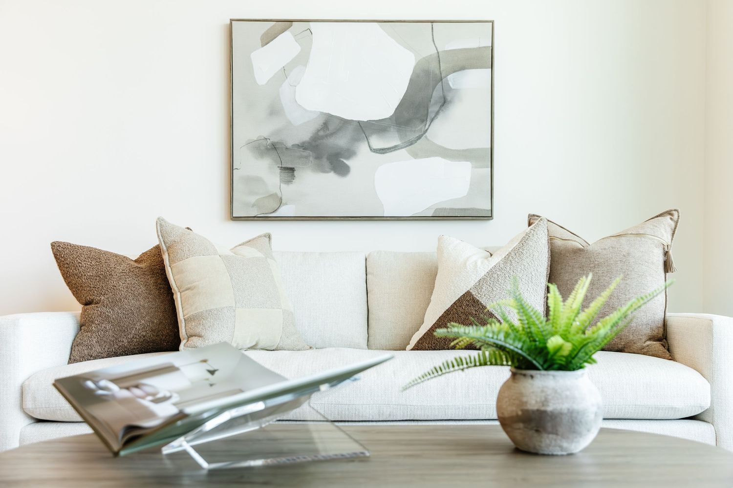 Modern living room interior with neutral decor, throw pillows, and minimalist artwork on the wall in a west Kelowna Airbnb