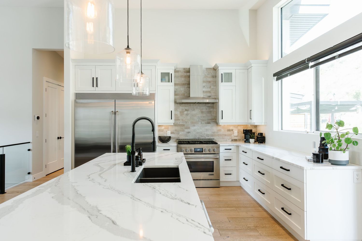 Bright white modern kitchen with marble countertops and pendant lighting in a west Kelowna Airbnb