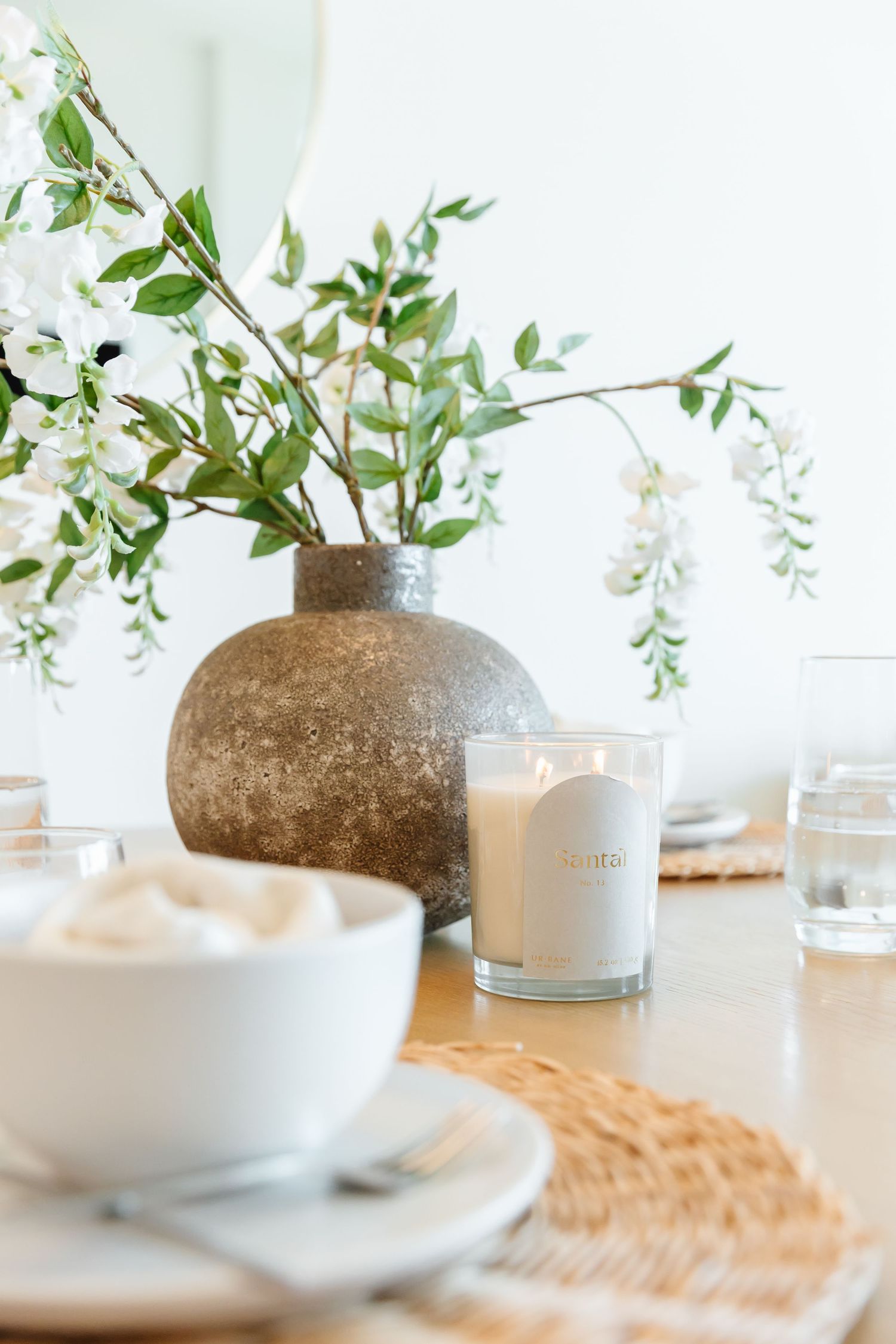 White ceramic bowls and vases with delicate floral arrangements on a wooden table in a west Kelowna Airbnb