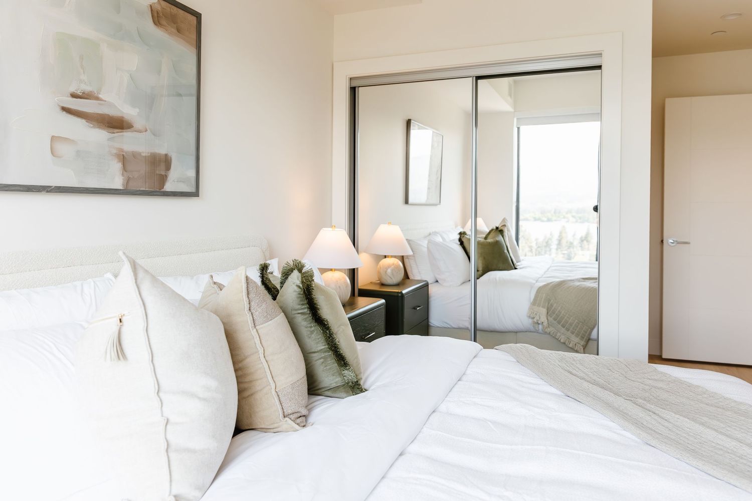 Serene bedroom interior with white bedding and natural light streaming through windows in a west Kelowna Airbnb