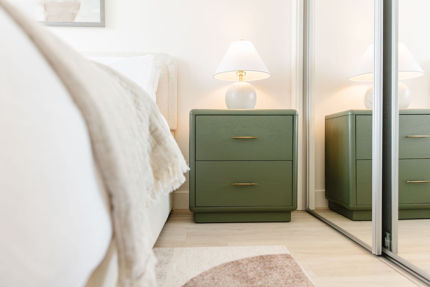 Minimalist bedroom featuring sage green nightstands and white bedding in a west Kelowna Airbnb