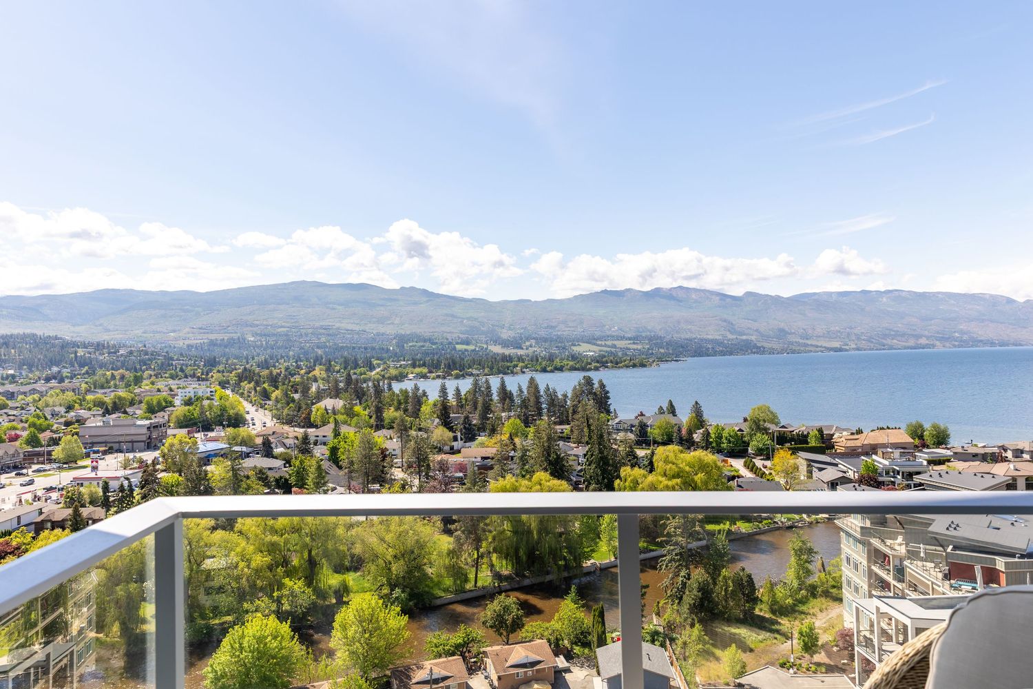 Panoramic view of a coastal city with mountains and water in the background from a Kelowna Airbnb balcony
