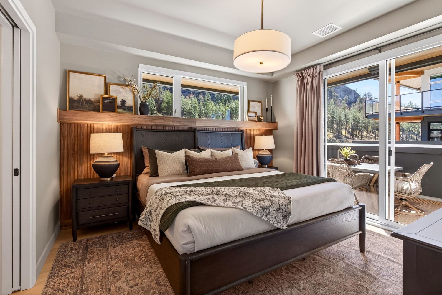 Cozy bedroom with dark wood furniture, mountain views, pendant light, and patio access.