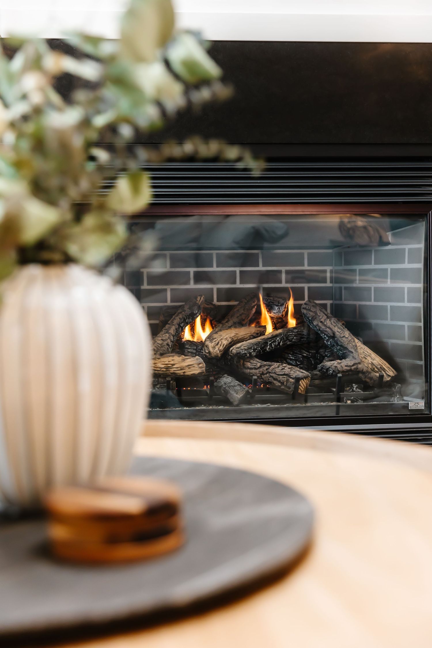 Modern gas fireplace with black tile surround and burning flames.