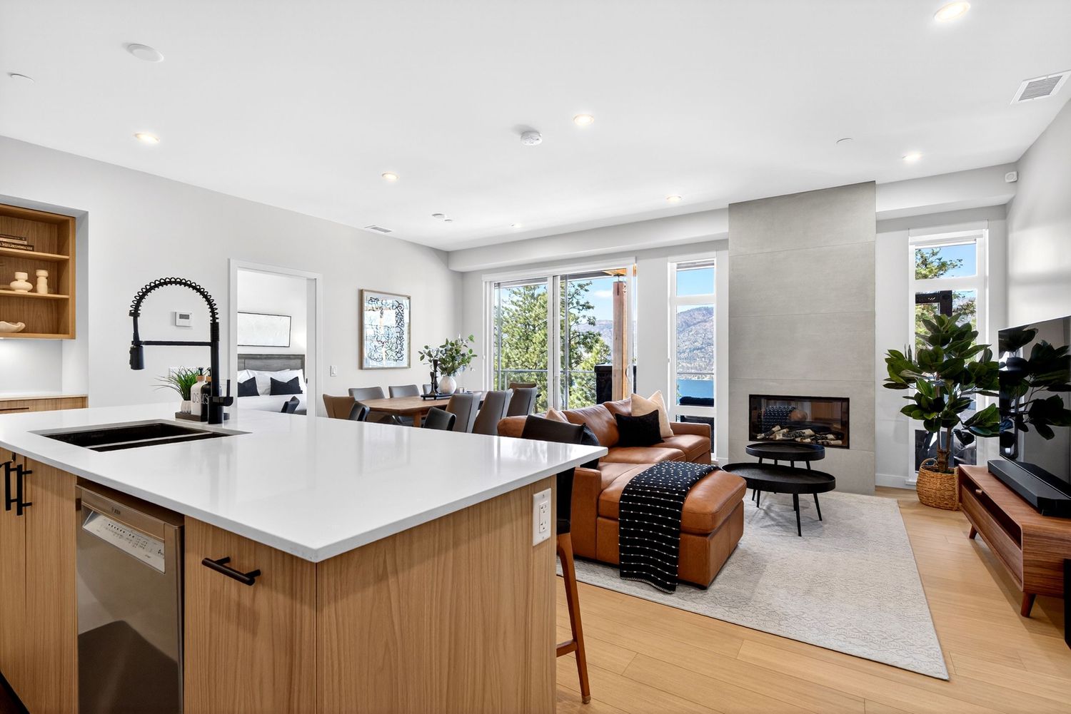 Modern open-concept kitchen and living room with white countertops, hardwood floors, and a cozy fireplace.