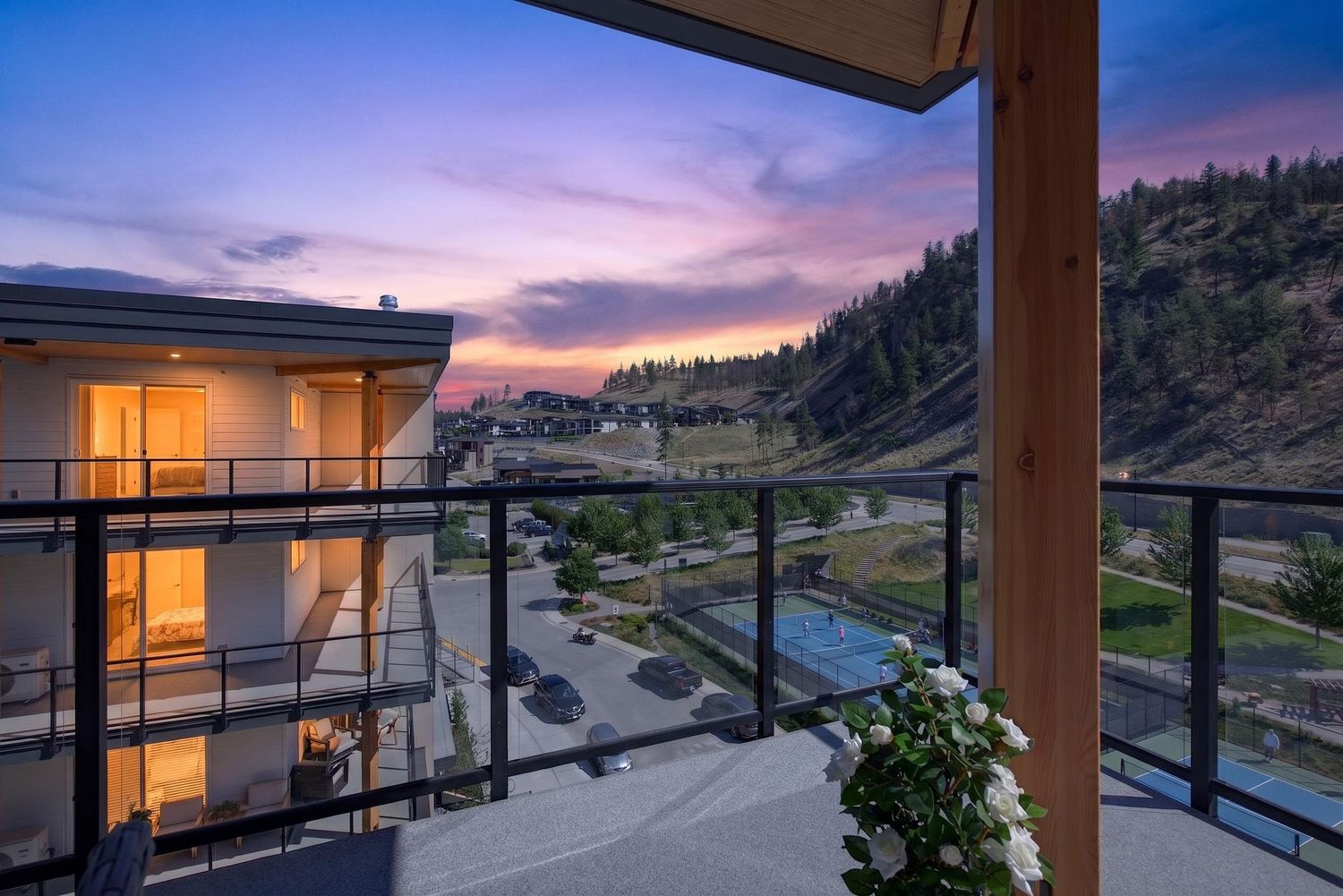 Stunning balcony view at sunset overlooking a hillside community with vibrant purple and orange skies.