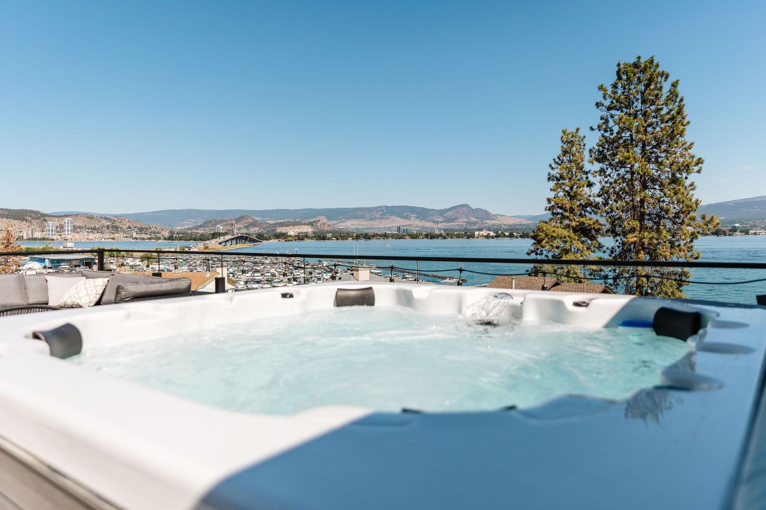 Rooftop hot tub overlooking mountain and lake landscape with clear blue skies.
