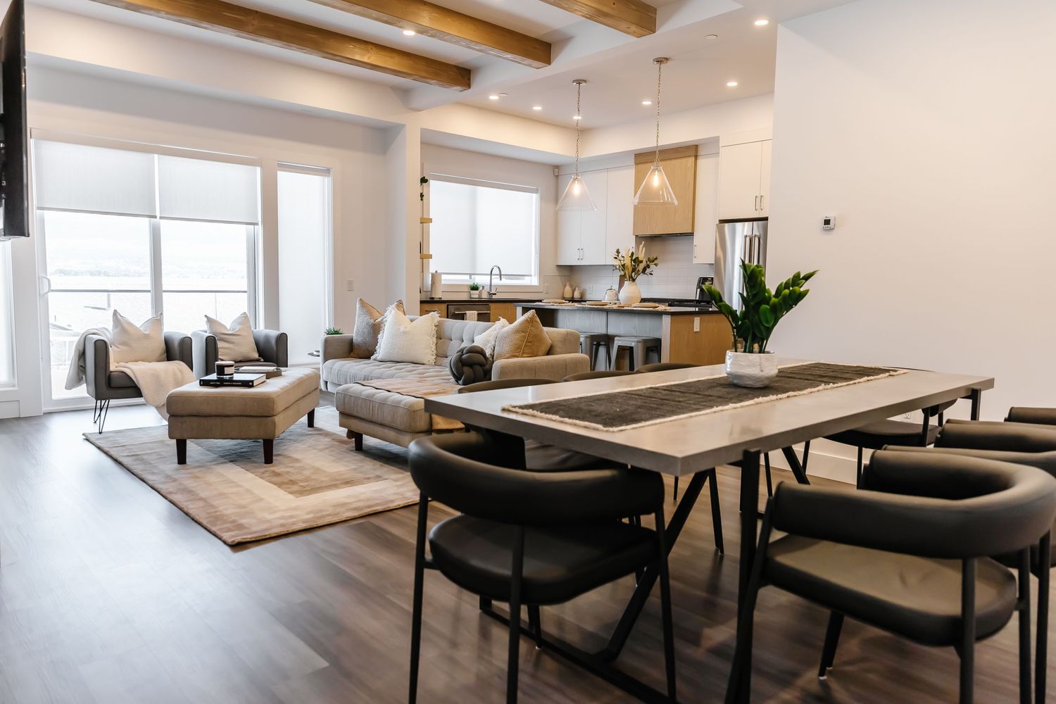 Modern open concept living space with exposed wooden beams and minimalist white decor.