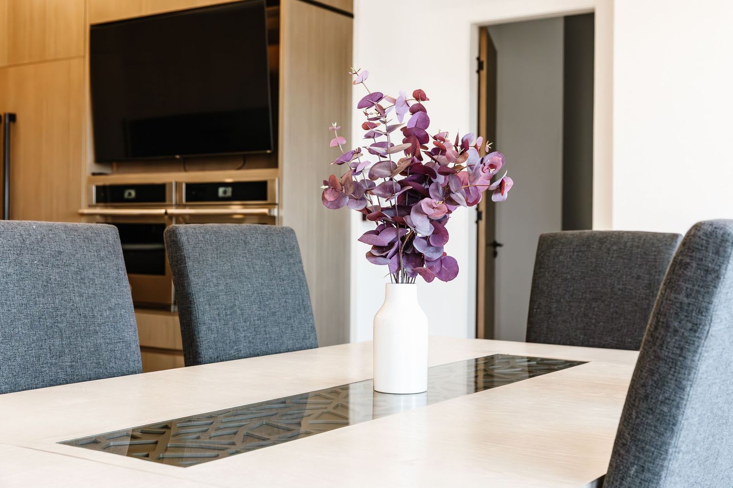 Contemporary dining area with gray chairs, wooden table, and purple floral arrangement in a west Kelowna Airbnb