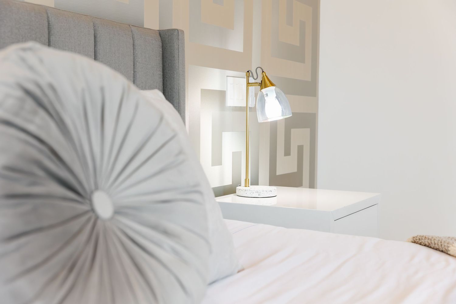 Luxurious bedroom detail showing plush gray circular decorative pillows and white bedding in a west Kelowna Airbnb