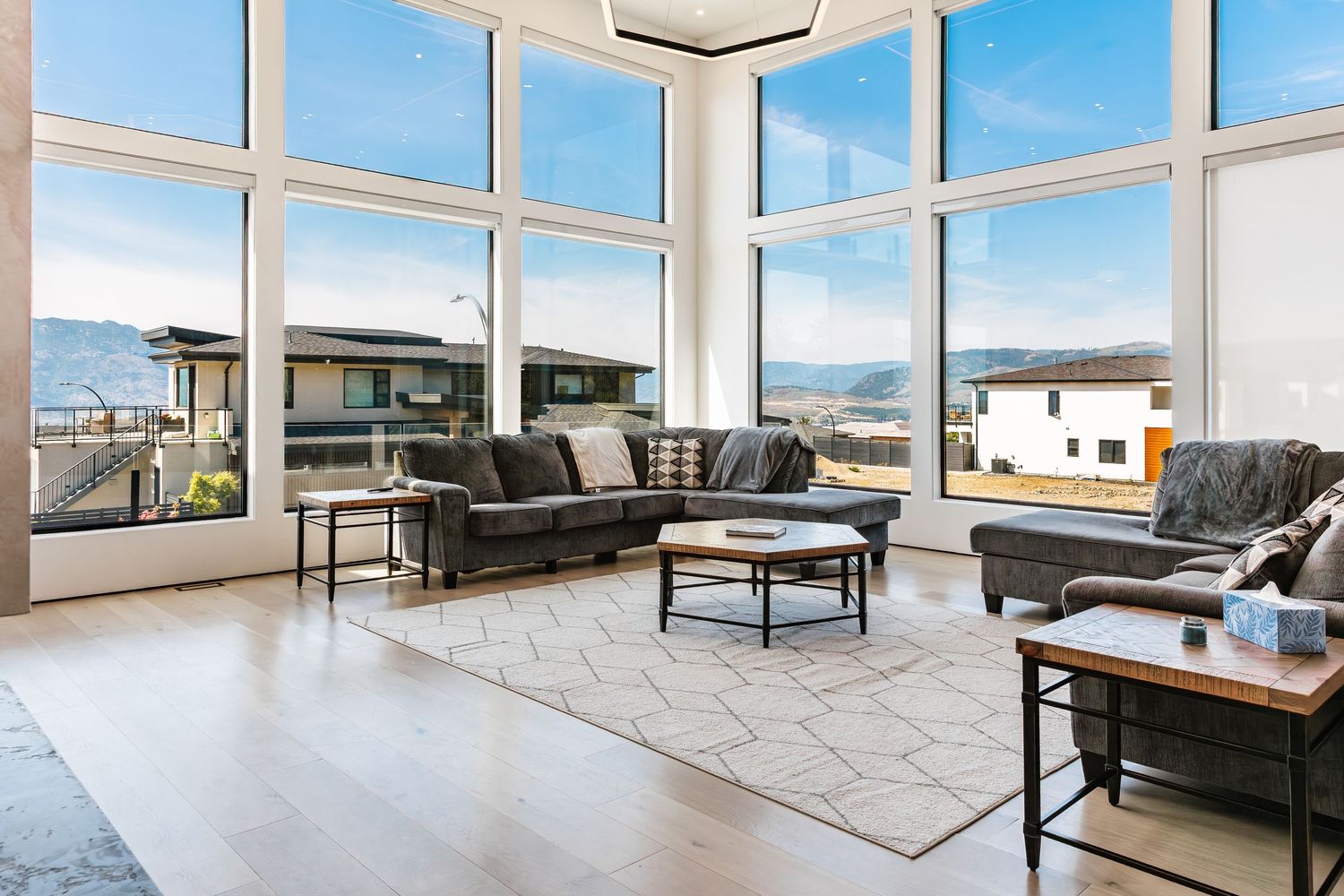Spacious living room with floor-to-ceiling windows offering panoramic mountain views and modern furnishings in a west Kelowna Airbnb