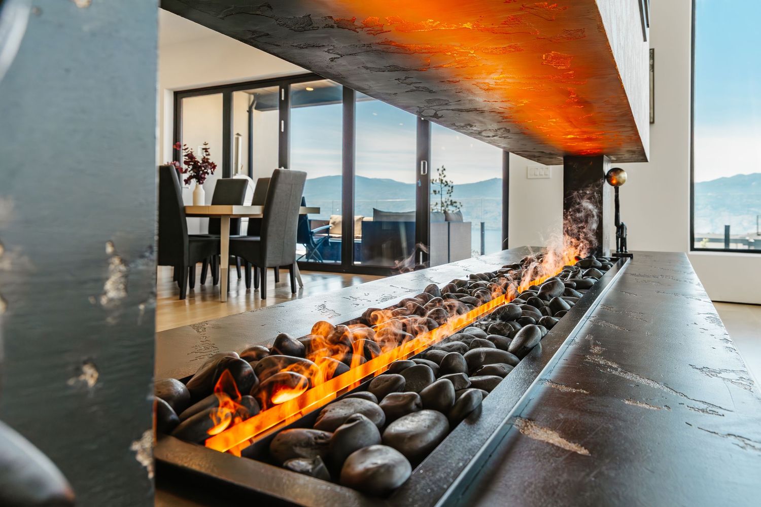 Modern linear gas fireplace with orange flames stretches along a sleek wall in an upscale living space in a west Kelowna Airbnb