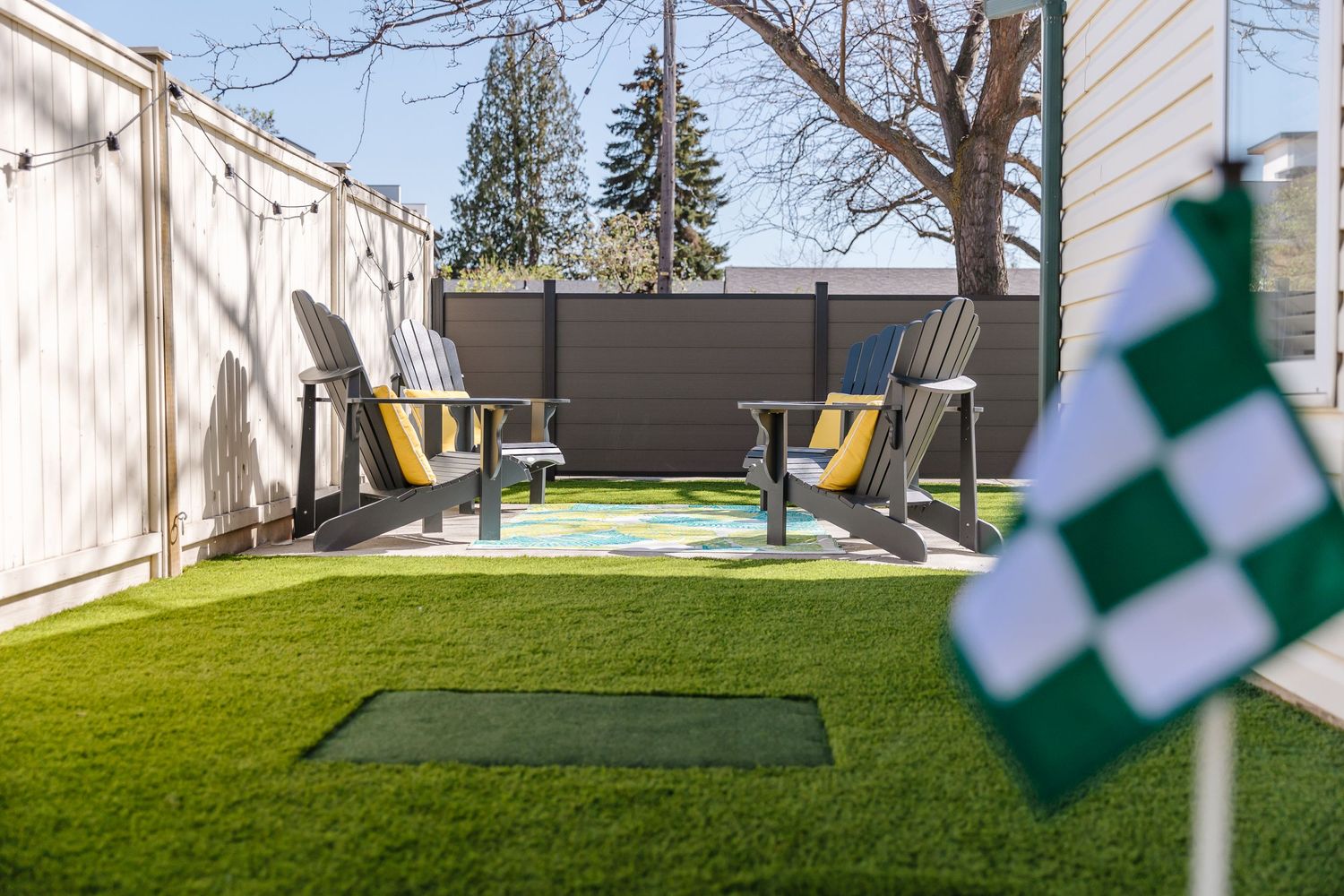 Modern backyard with artificial turf and checkered flags visible in the foreground.
