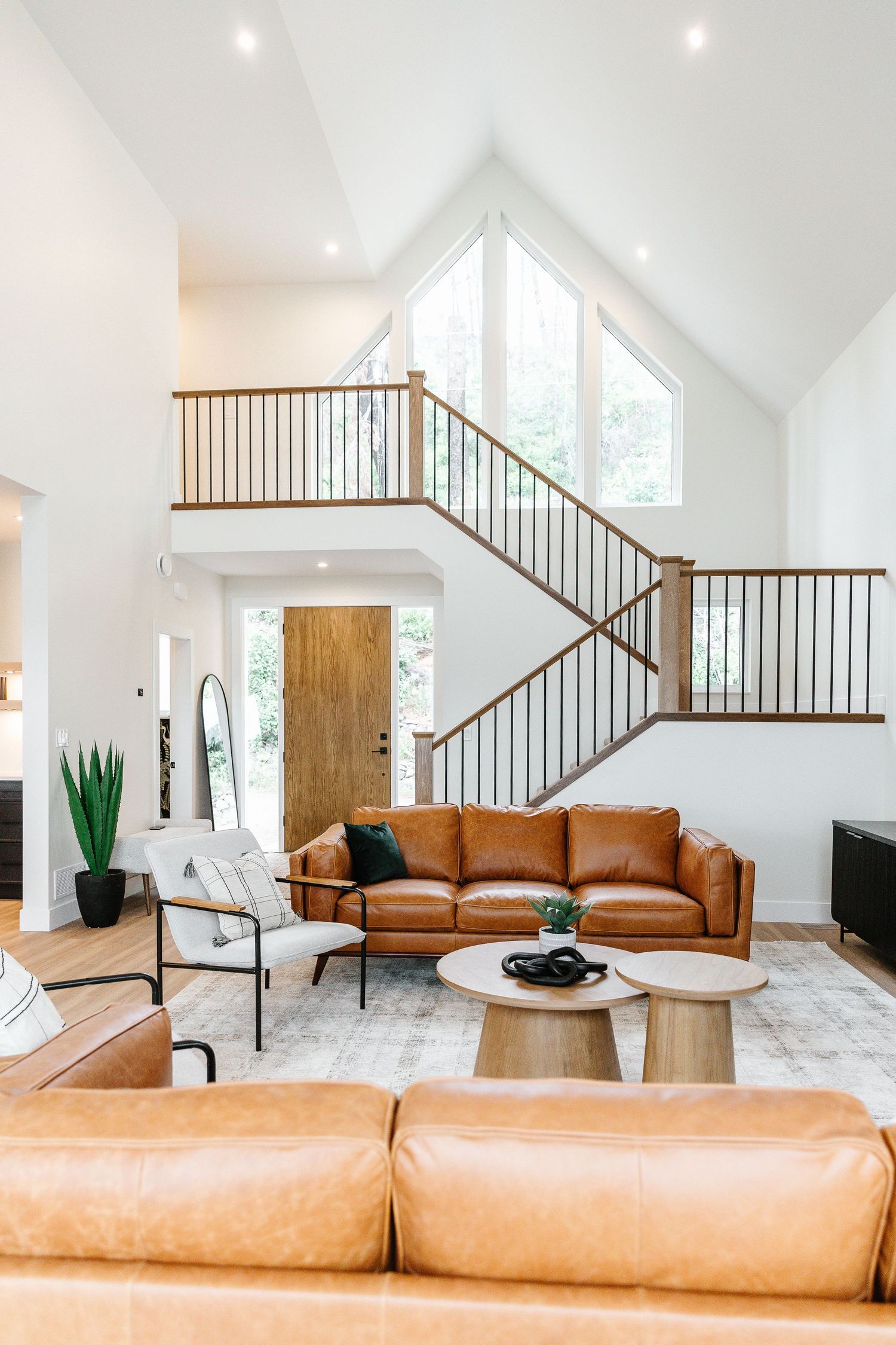 Bright living space with tan leather sectional sofa and cathedral ceiling with wooden accents Airbnb in West Kelowna