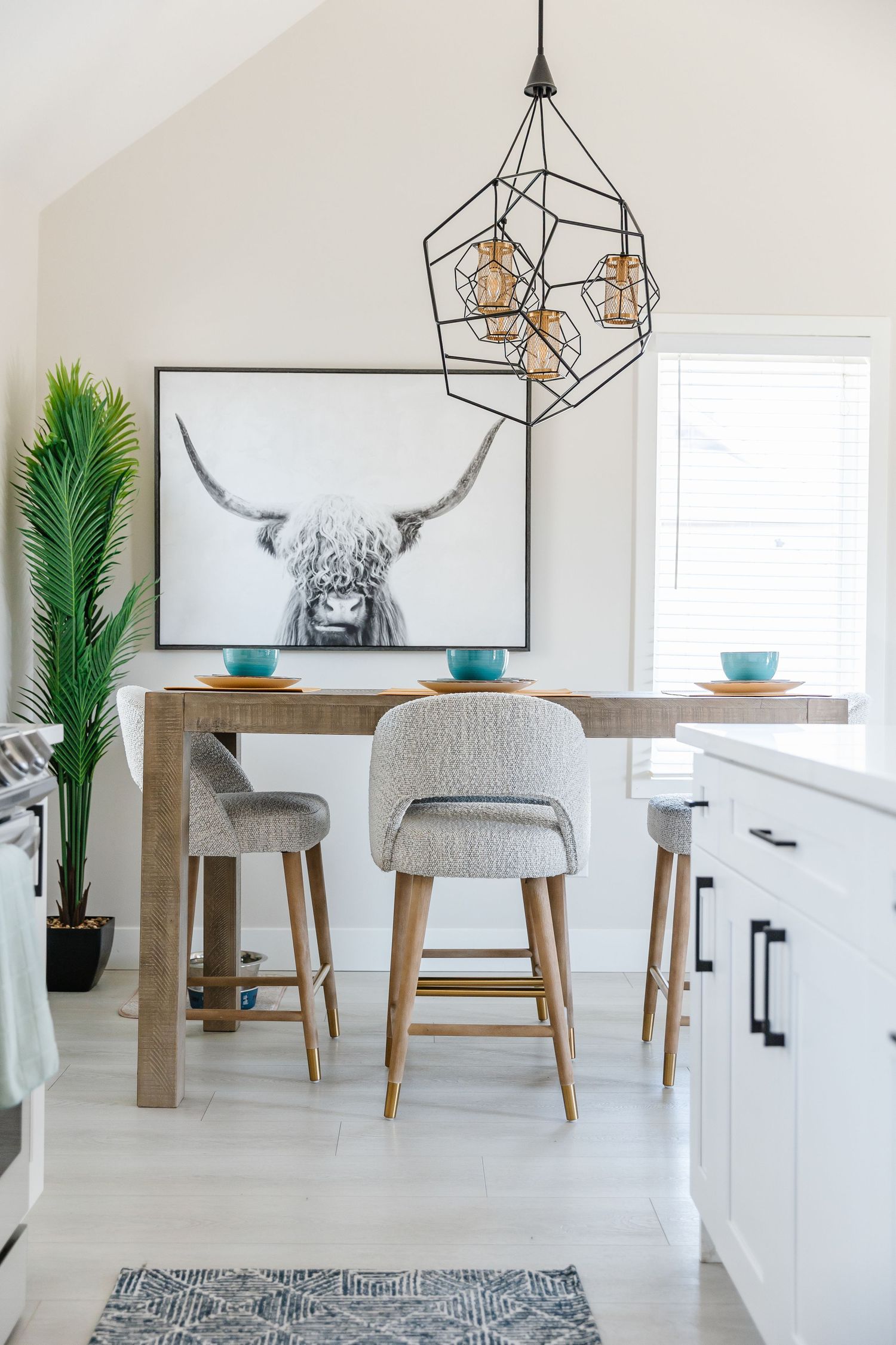 Minimalist dining space featuring geometric light fixtures, gray chairs, and modern wall art.