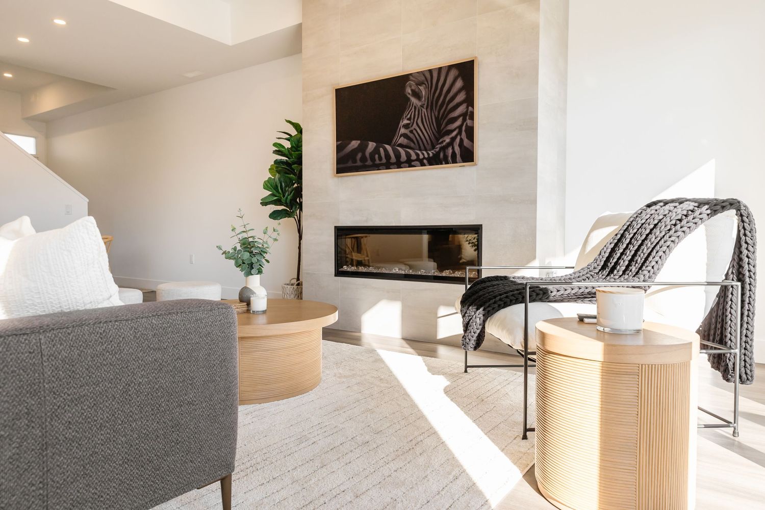Modern living space with grey sofa, built-in fireplace, and natural wood accent tables.