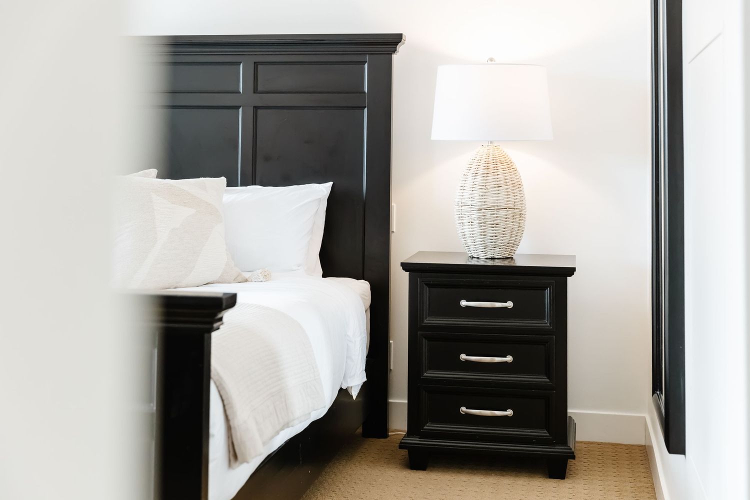 Black bedroom furniture set against white walls featuring a nightstand and dresser in a west Kelowna Airbnb