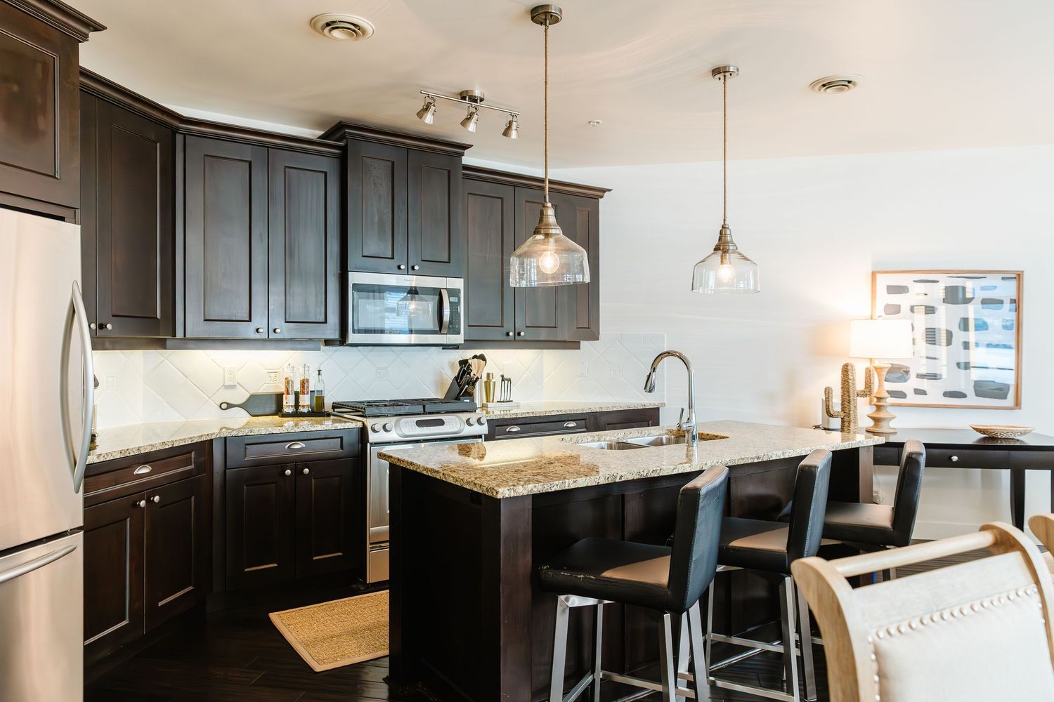 Modern kitchen with dark cabinets, pendant lights, and granite countertops in an open concept layout in a west Kelowna Airbnb