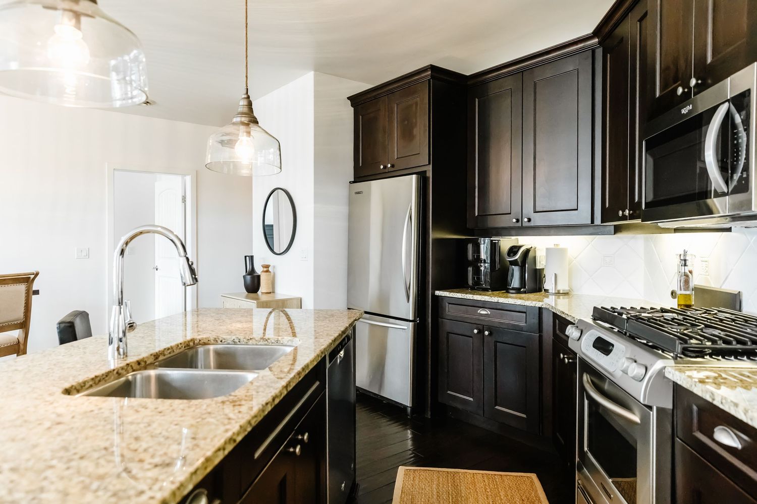 Elegant kitchen featuring dark cabinets, granite countertops, and stainless steel appliances in a west Kelowna Airbnb