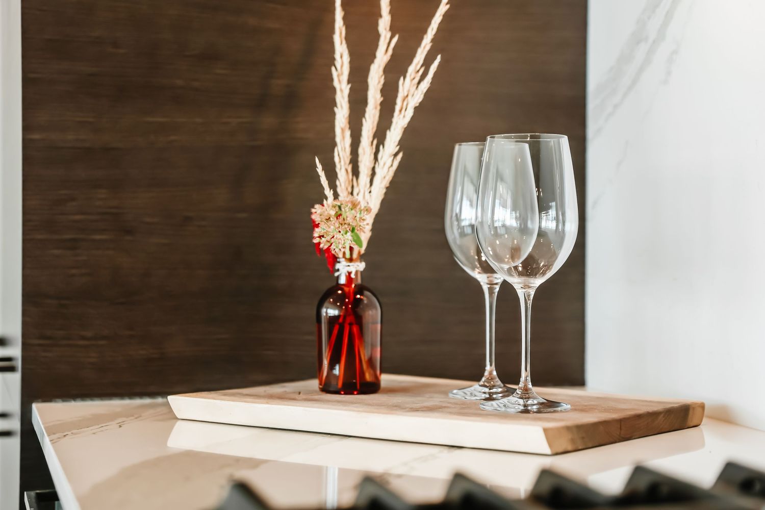Elegant dining table setting with wooden accent wall and wine glasses.
