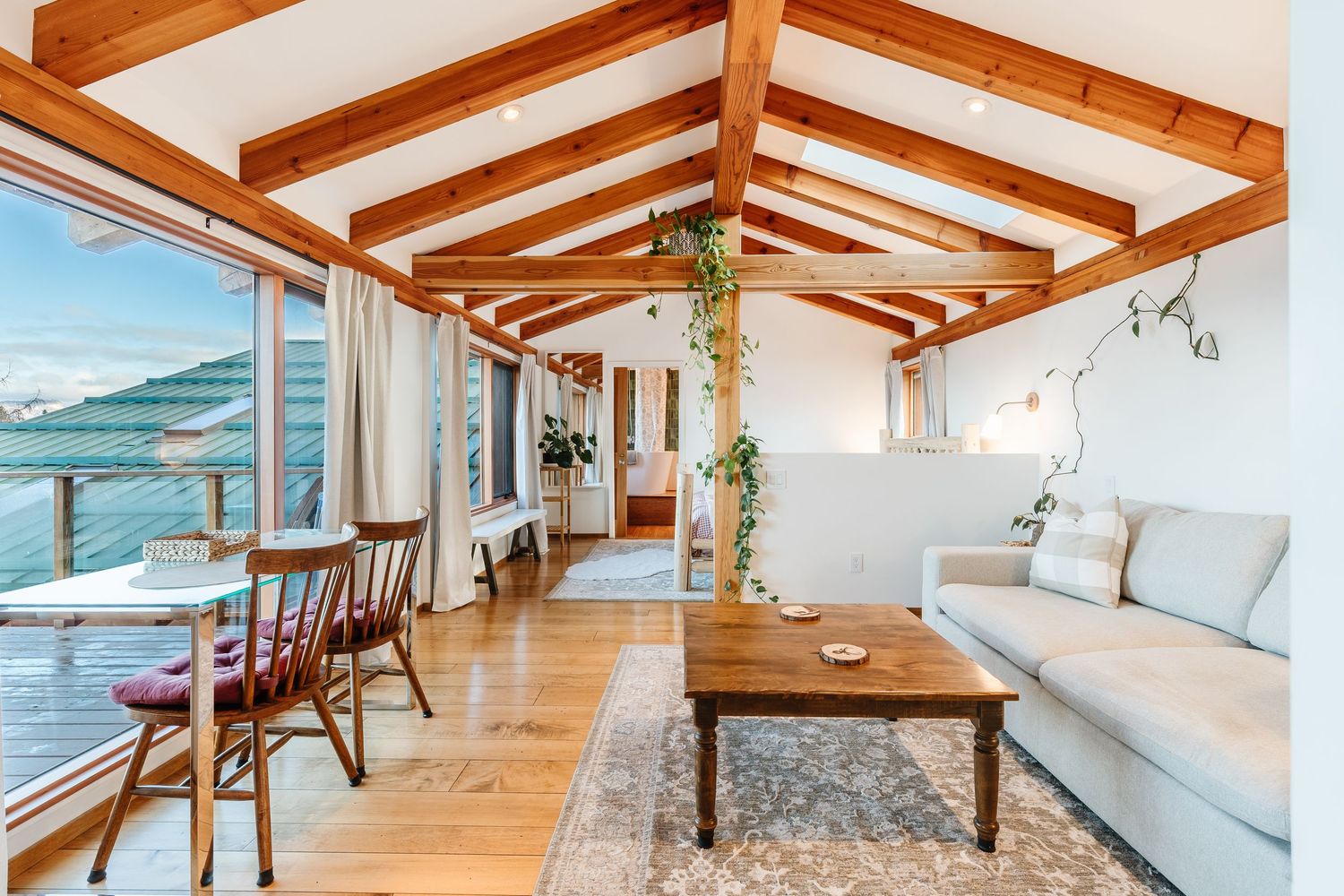 Modern apartment interior with exposed wooden beams, white walls, and hardwood floors showcases a bright, open-concept design.