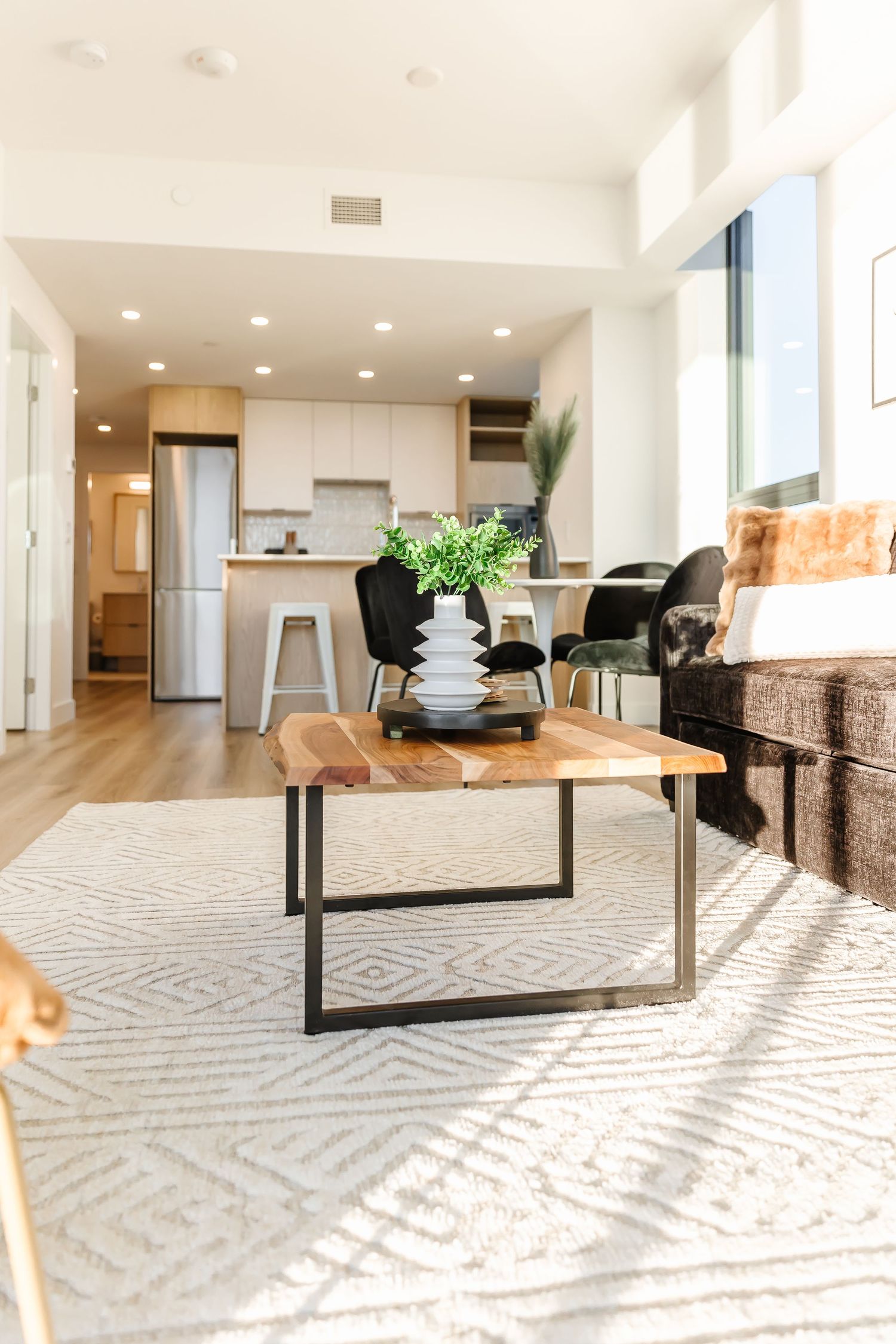 Modern living room with geometric patterned carpet and contemporary furniture in bright white space.