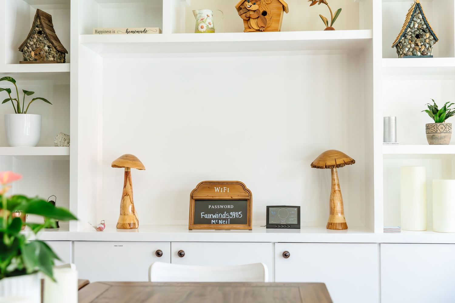 White built-in shelving displaying decorative items, plants, and artwork in a modern home.