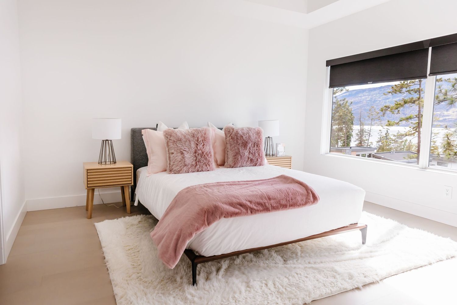 Bright modern bedroom with pink accents and large windows.