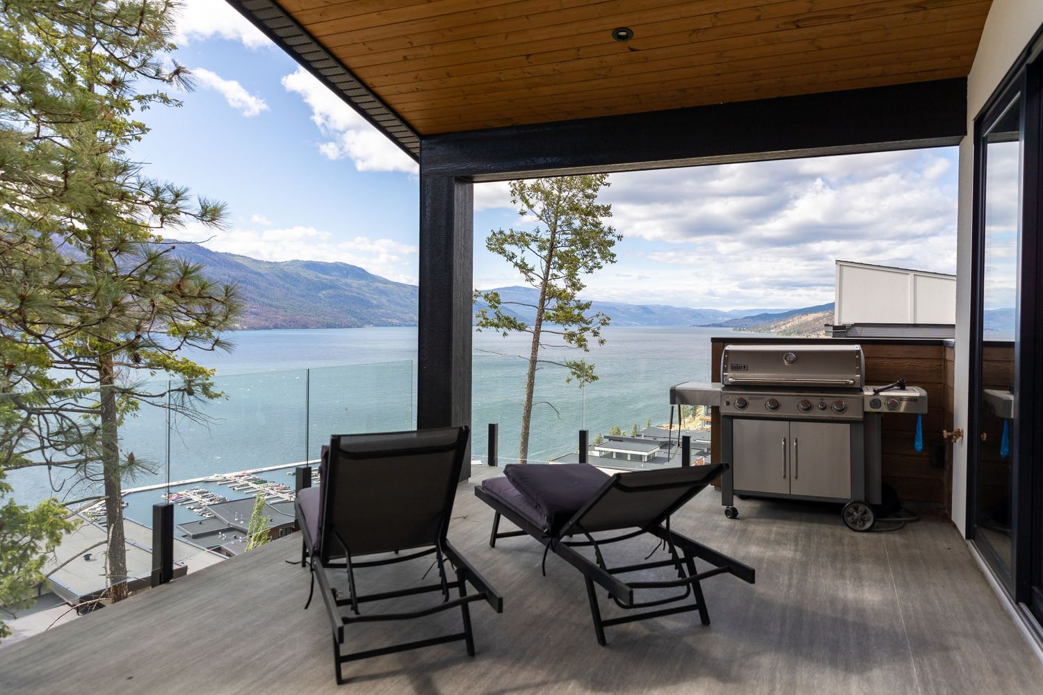 Outdoor deck with lounge chairs overlooking a scenic mountain lake view.