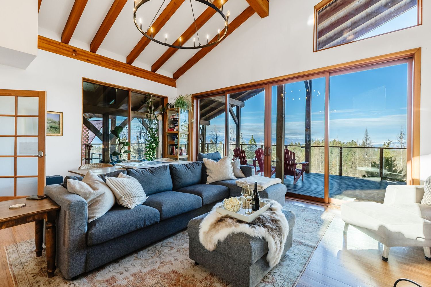 Modern living room with exposed wood beams, large windows, and ocean views features a blue sofa and contemporary decor.