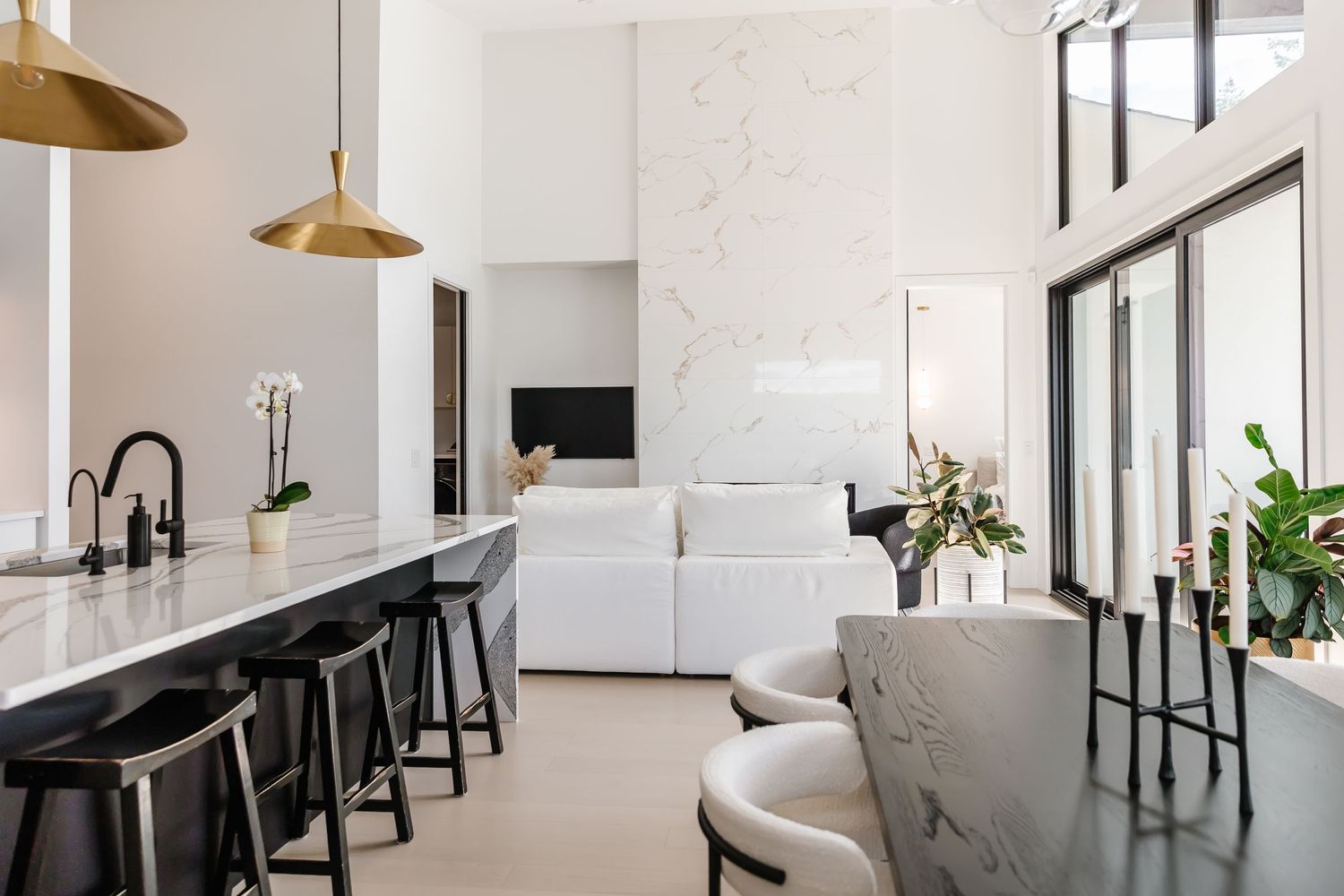Sleek white kitchen with modern appliances and large windows.