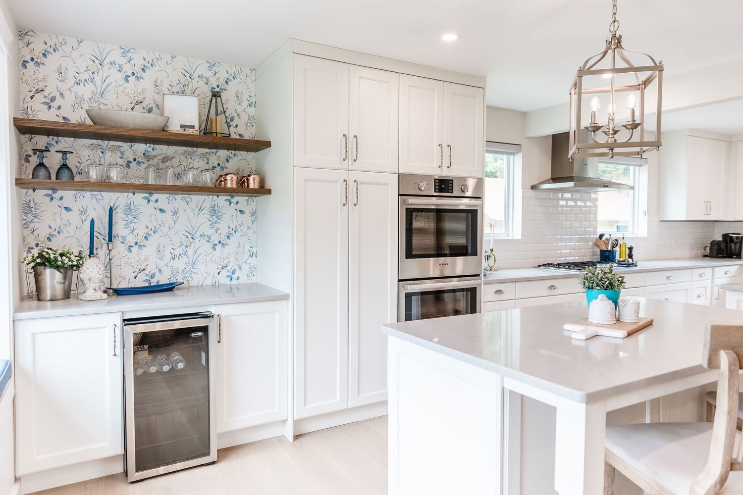 Bright white kitchen with marble countertops and pendant lighting.