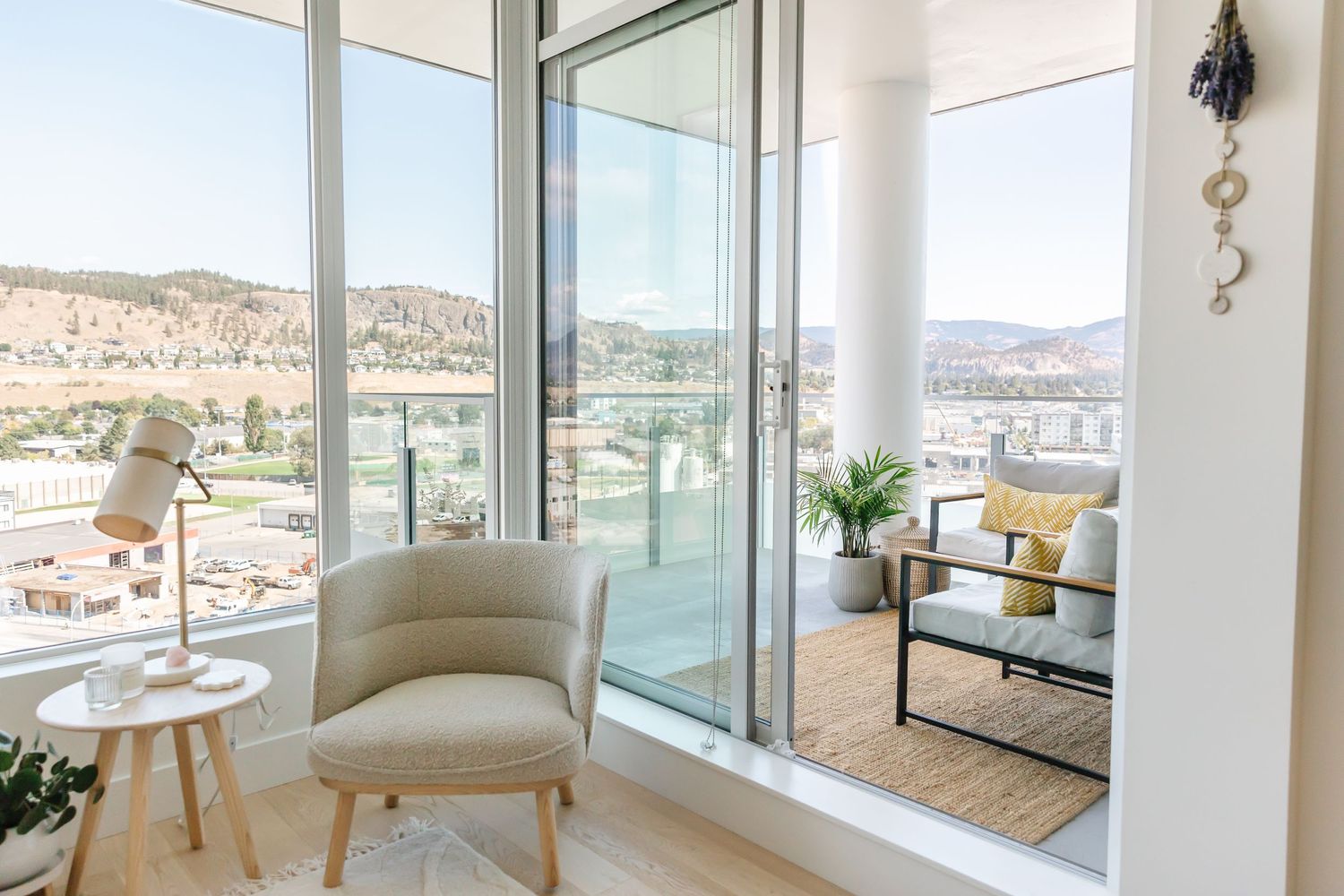 Bright corner balcony with panoramic mountain views and modern white accent chair.