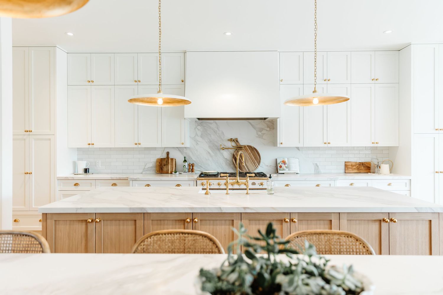 Modern white kitchen with marble countertops, gold pendant lights and natural wood accents in a west Kelowna Airbnb