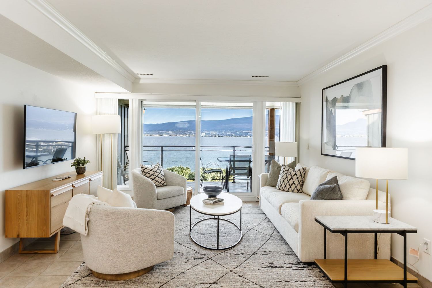Modern white living room with panoramic windows showcasing mountain views and minimalist furniture arrangement.