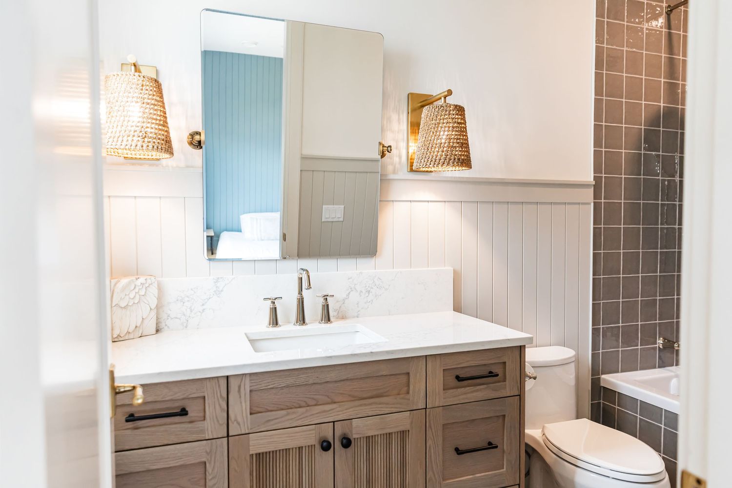 Contemporary bathroom featuring gray tile, white paneling, and woven pendant lights in a west Kelowna Airbnb