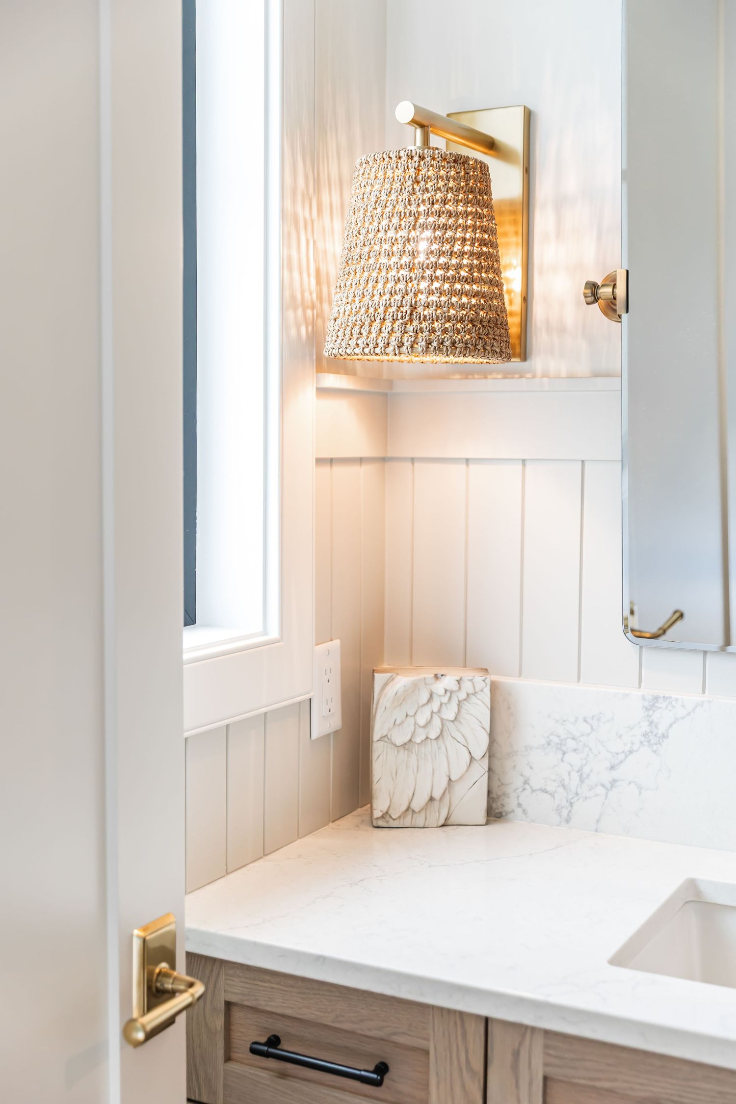 Elegant bathroom vanity with woven pendant lights, white paneling, and black hardware in a west Kelowna Airbnb