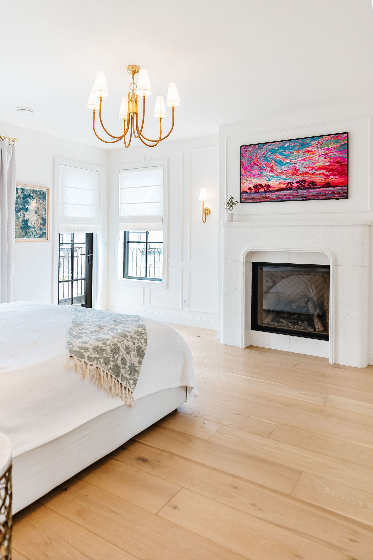 Spacious living room with light wood floors, white walls, and colorful artwork above a modern fireplace in a west Kelowna Airbnb