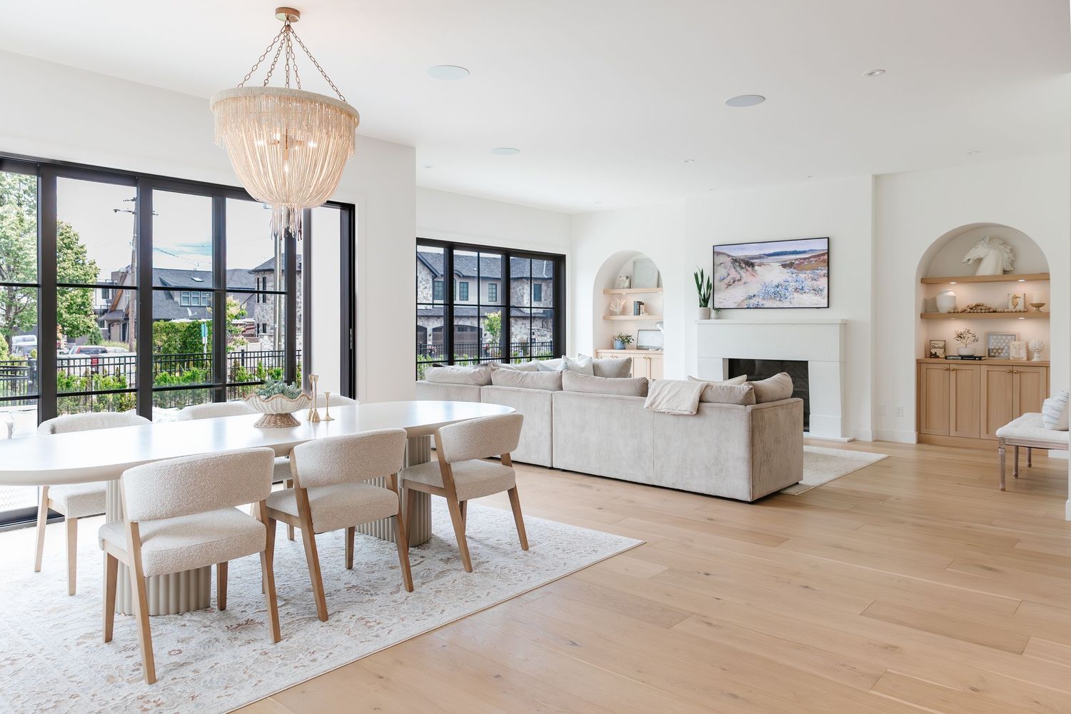 Airy dining area with crystal chandelier, light wood floors, and large windows letting in natural light in a west Kelowna Airbnb